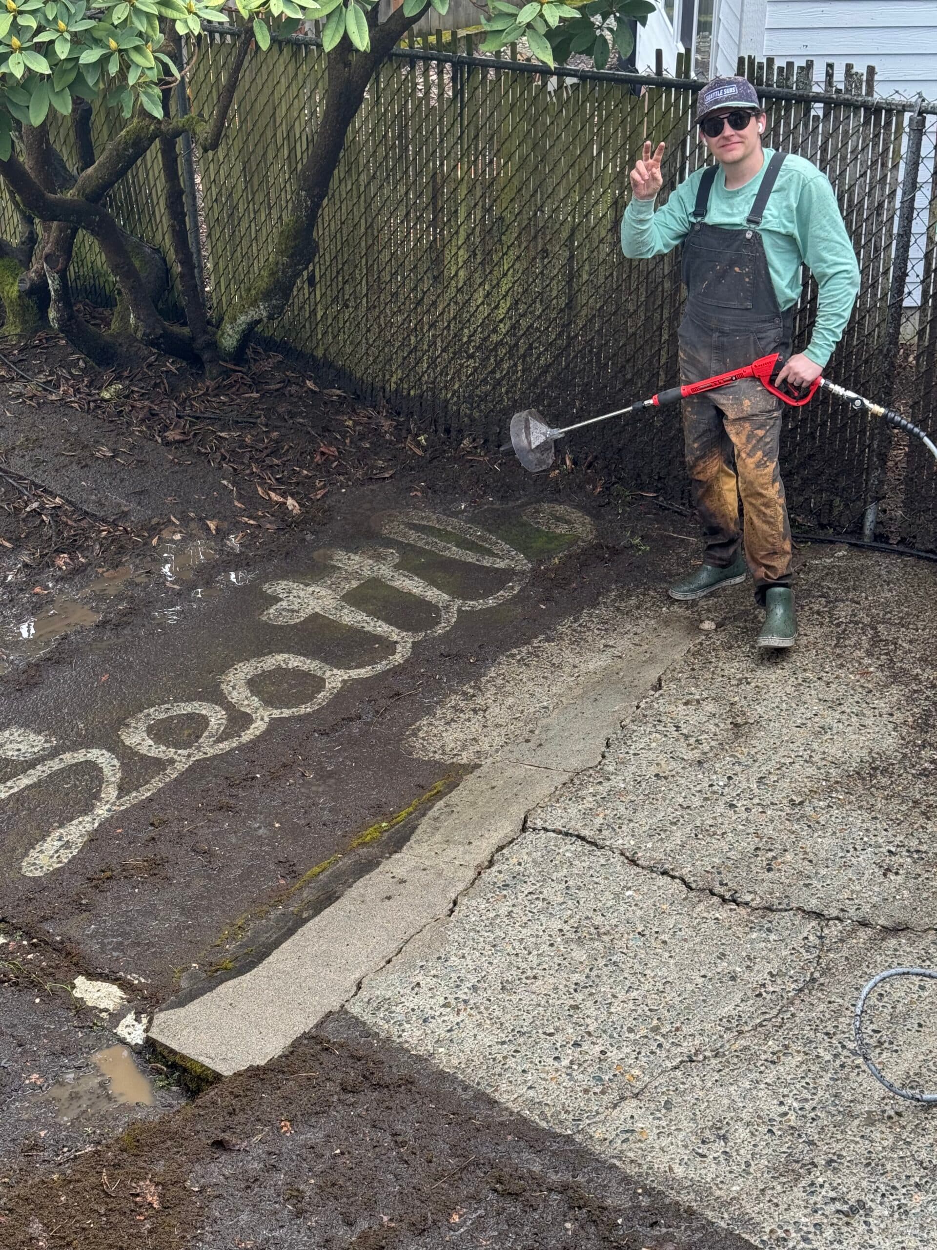 Seattle Suds crew member next to the word Seattle pressure washed into grimy concrete