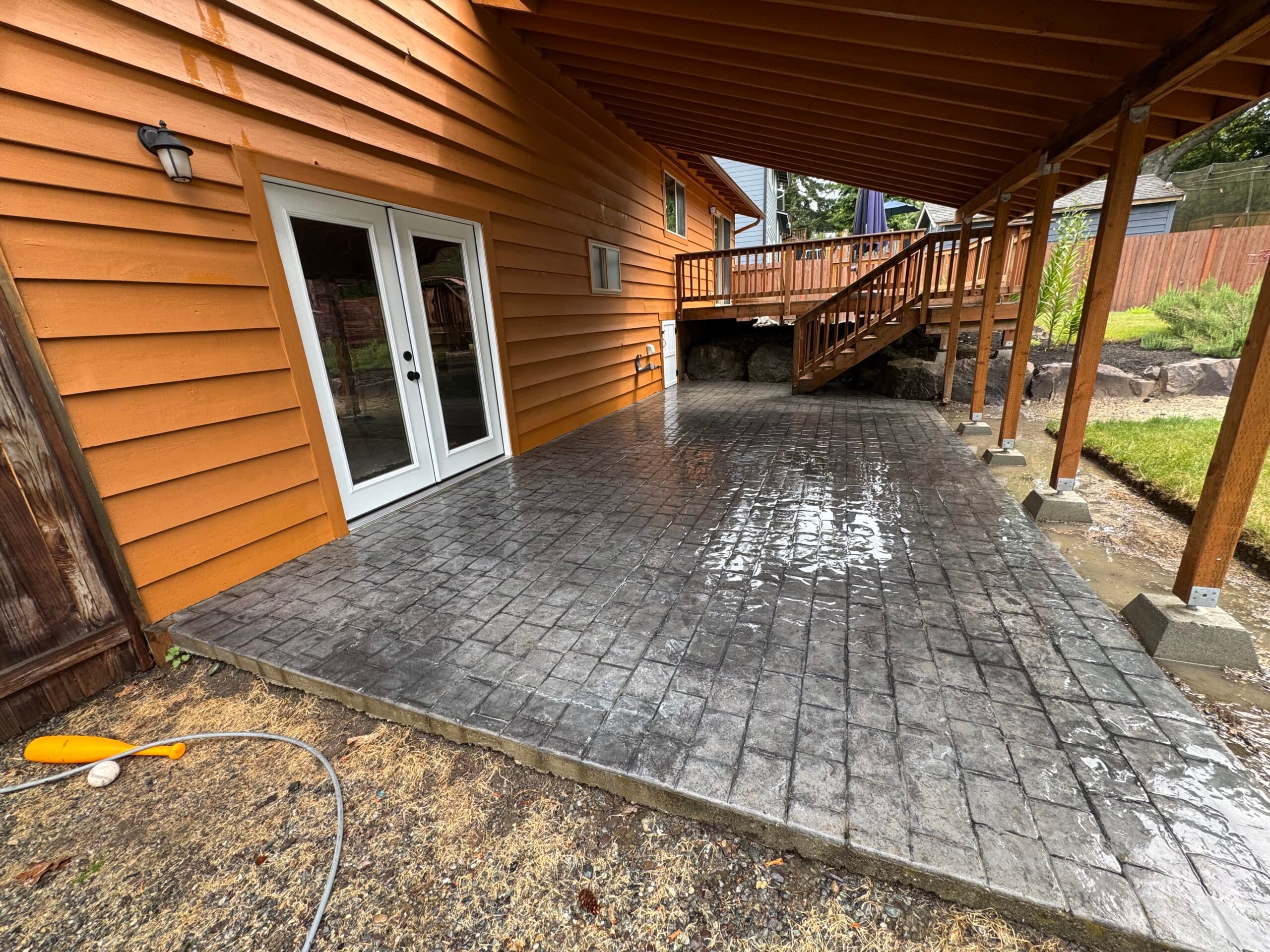 Freshly washed dark stamped-concrete patio glistening wet